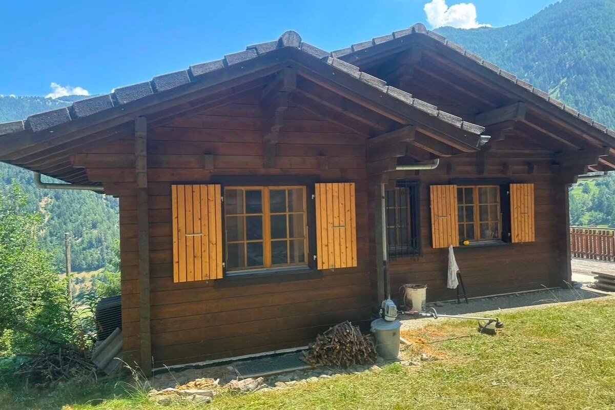Chalet avant travaux, madriers grisés et volets jaunis