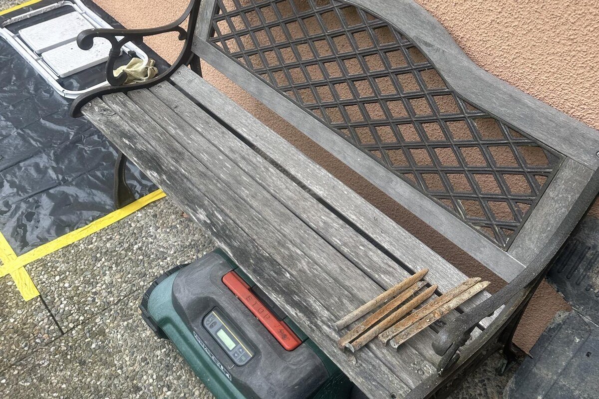 Banc de jardin démonté, lattes de bois grisées et fonte ternie