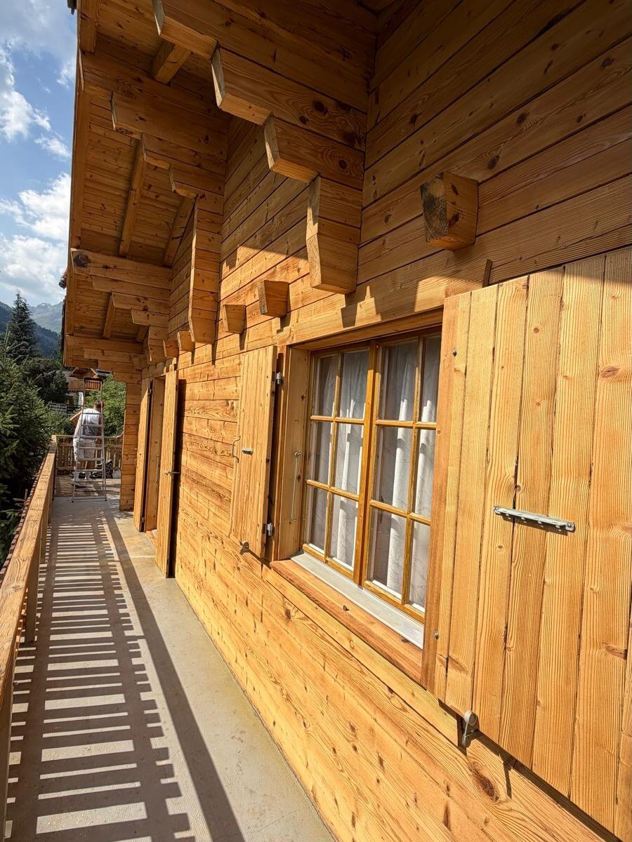 Façade latérale du chalet en enfilade, bois sablé et encadrements repris