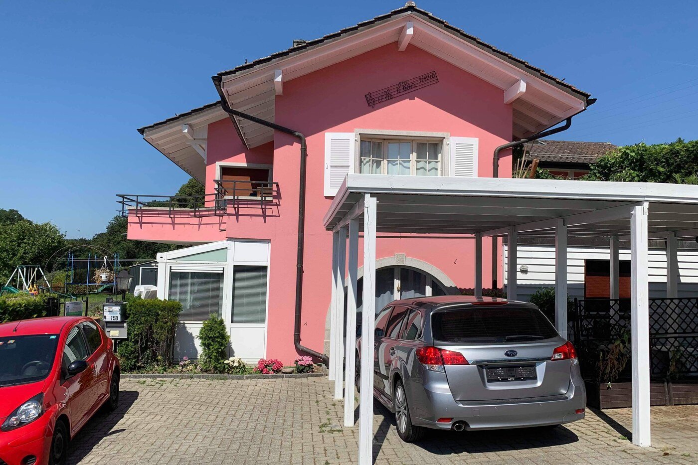 Villa aux façades roses avec carport à structure bois repeinte en blanc