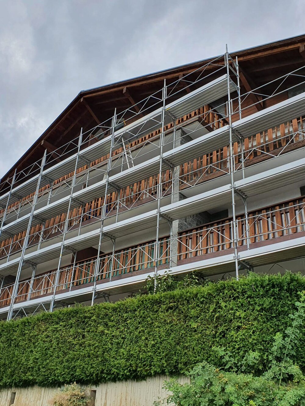 Immeuble de quatre niveaux entièrement échafaudé, balcons en bois, à Crans-Montana